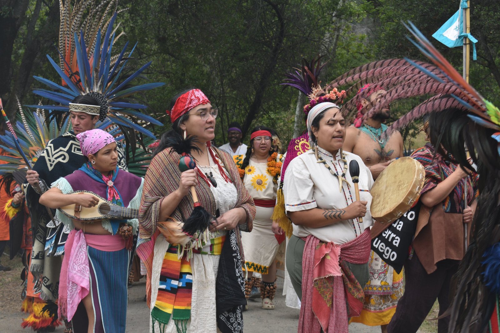 Community members singing and drumming in ceremonial regalia.